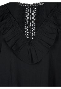 Blouse noire avec un profond décolleté en V orné de dentelle et de volants, fermeture à boutons sur le devant, tissu texturé.