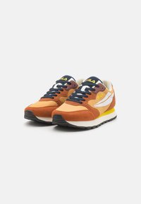 Fila sneakers med en överdel i orange mocka och mesh, svarta snören, vita accenter och gula logotyper på tungan och sidan. Tjock svart sula.
