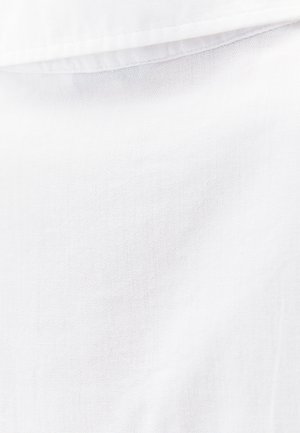 Valkoinen puuvillakangas, jossa on pehmeä ja teksturoitu pinta. Se on sileä viimeistely, jossa on hienovaraisia vaieluja langan tiheydessä.