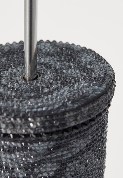 Oggetto cilindrico nero con texture, dotato di una asta metallica liscia al centro e di una superficie decorata con piccoli elementi sfaccettati.