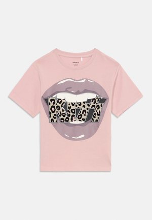 T-shirt rose clair à manches courtes avec un graphique de lèvres violettes et un texte "KISS" en imprimé léopard sur la zone des dents à l'avant.