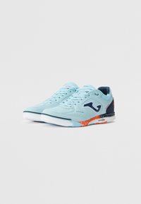 Scarpe sportive di colore azzurro chiaro con upper testurizzato, dettagli in blu navy e accenti arancioni. Presentano una suola bianca con motivi antiscivolo.