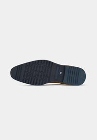 Sola de um sapato castanho mostrando um padrão preto na sola, tamanho 40 indicado perto do calcanhar, contra um fundo branco simples.