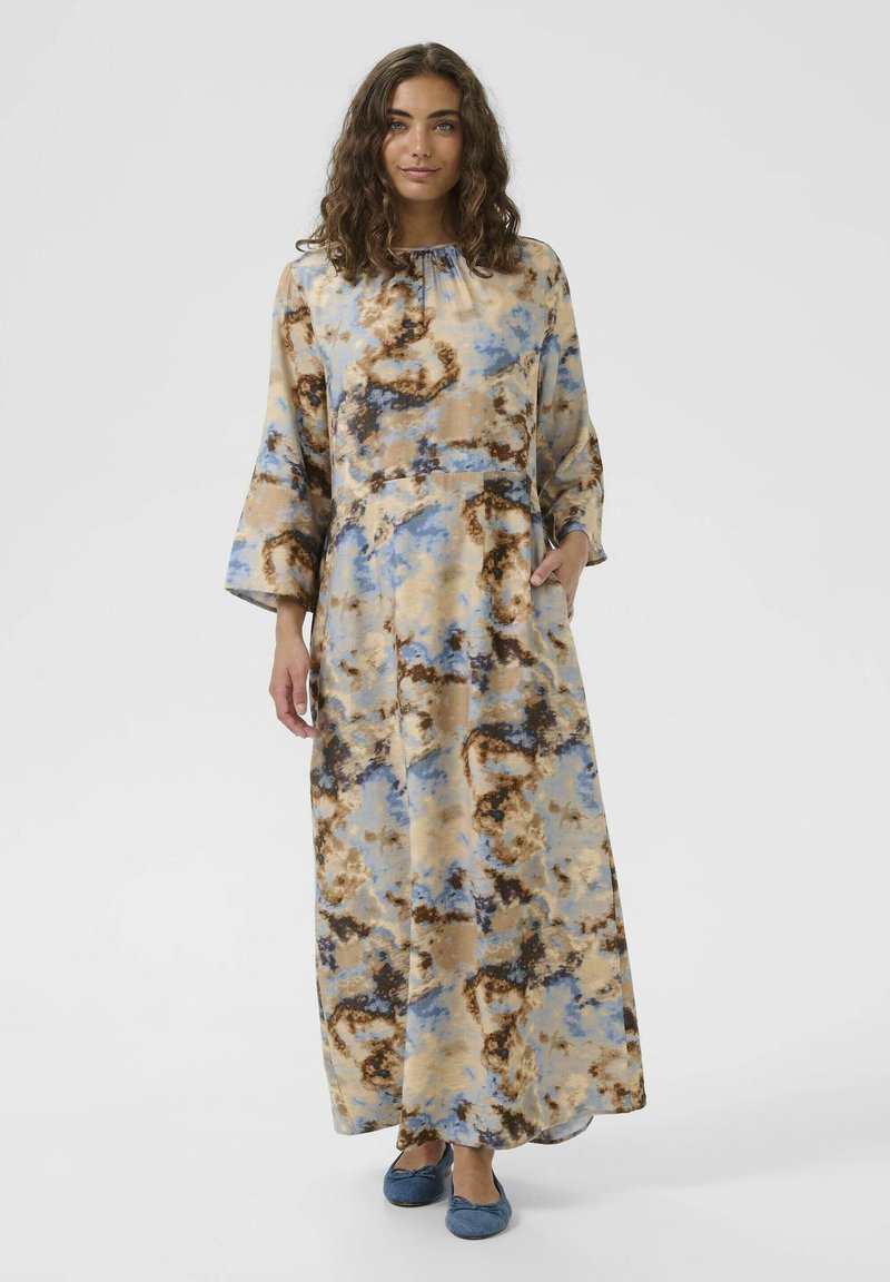 Pitkä, virtaava mekko, jossa on ruskea, sininen ja beige abstrakti kuvio. Mukana pitkät hihat, kerrostettu kaula-aukko ja sivutaskut.