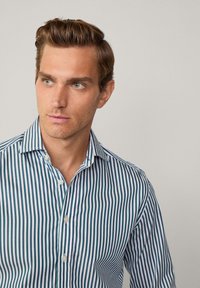 Button-up shirt with vertical stripes in navy blue and white, featuring a classic collar and a slim fit design.