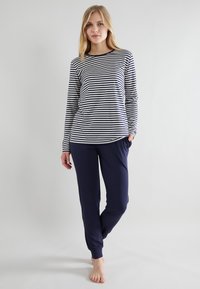 Top de manga larga a rayas en azul marino y blanco, combinado con pantalones azul marino. Ambos hechos de una tela suave y elástica con un corte relajado.