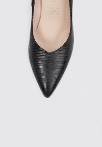 Zapato de punta negra con un patrón de cocodrilo texturizado, que cuenta con un forro interior suave y una sutil marca en la plantilla.