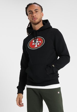 Black hoodie with a large red and white San Francisco logo. Features a front pocket, drawstring hood, and ribbed cuffs. Paired with green pants.