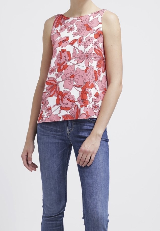 Top senza maniche floreale in rosa e bianco; presenta grandi fiori rossi e rosa, scollatura rotonda e una vestibilità rilassata. Abbinato a jeans blu.