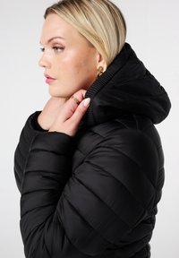 Zwarte donsjack met een quilted ontwerp, hoge kraag met capuchon en een soepele textuur. Accentueert een strak figuur.
