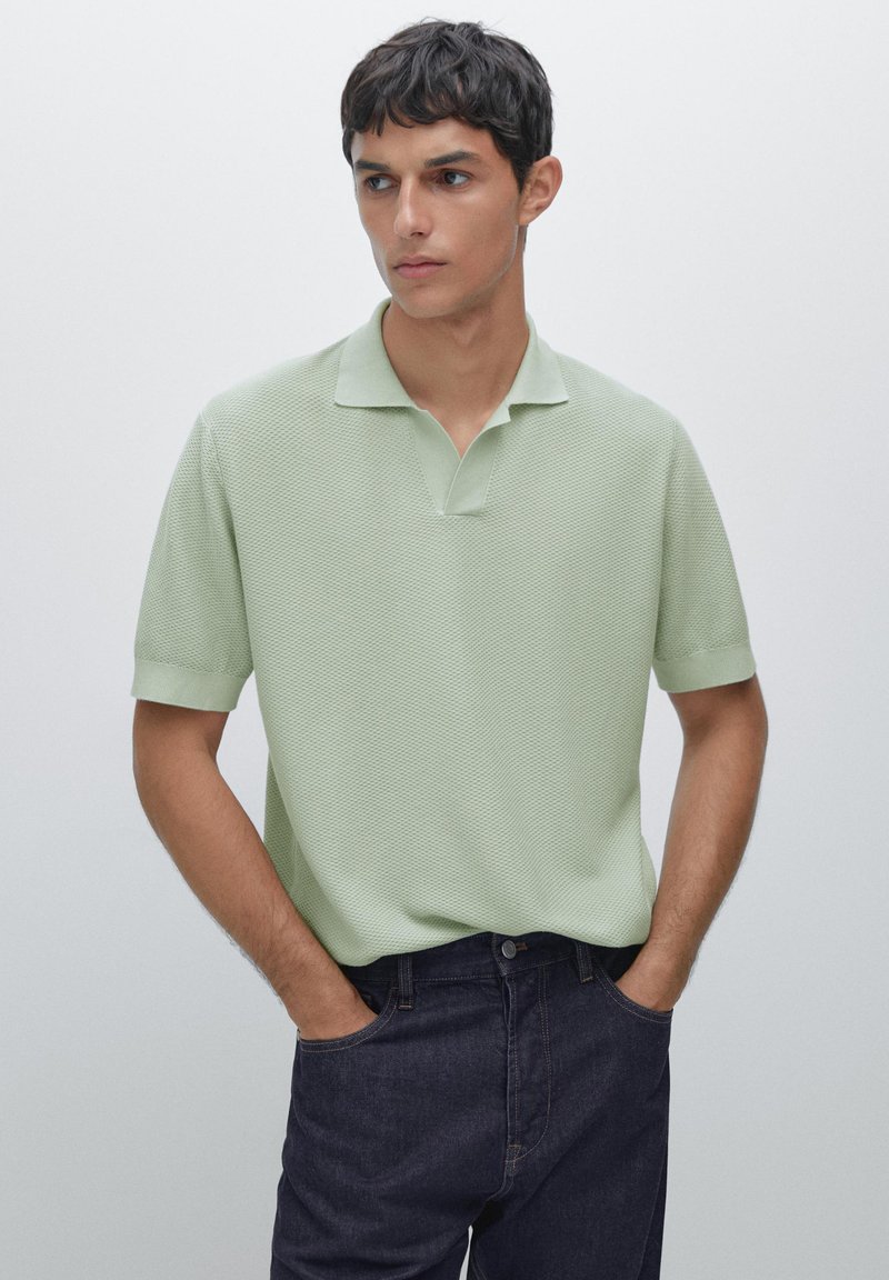 Polo shirt corto a maniche corte verde chiaro con un motivo tessutato, dotato di un colletto piatto e una vestibilità rilassata, abbinato a jeans in denim scuro.