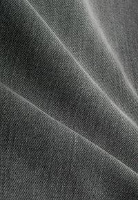 Grijze denimstof met een gladde textuur, met zichtbare keperweeflijnen en subtiele variaties in schaduw.