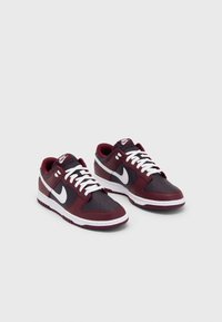 Tenisky Nike s vínovým a tmavě šedým barevným provedením, syntetickými materiály, bílými tkaničkami a výrazným bílým logem swoosh.