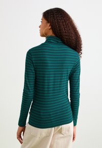 Langærmet turtleneck top med mørkegrønne og marineblå vandrette striber, lavet af blødt stof med en tætsiddende pasform.