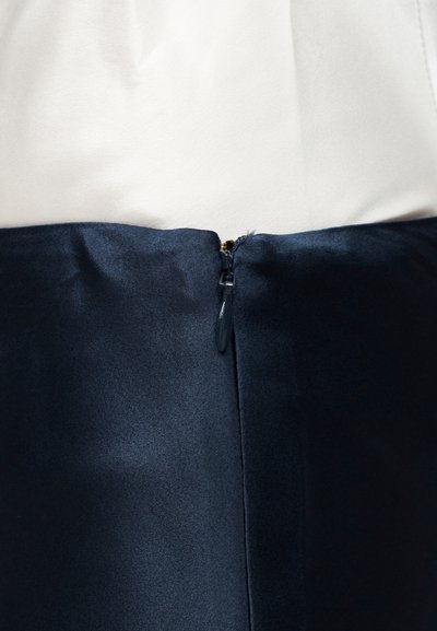 Κοντινό πλάνο μαύρου φερμουάρ σε δίχρωμο φόρεμα με λευκό επάνω μέρος και μαύρο κάτω μέρος.