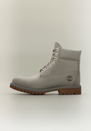 Bottine grise en cuir à lacets avec col rembourré et semelle crantée marron, logo arbre Timberland embossé sur le côté extérieur.