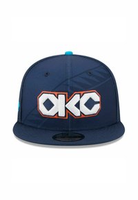 Casquette snapback bleu marine avec un logo "OKC" en blanc et orange. Tissu lisse, visière plate, avec un bouton accent turquoise sur le dessus.