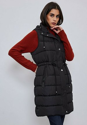 Veste matelassée noire avec capuche, dotée d'une taille cintrée, de poches zippées et de boutons-pression. Texture lisse et design léger.