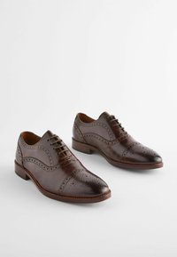 Brown leather dress shoes with a smooth finish, decorative perforations, a classic lace-up design, and a slightly pointed toe.