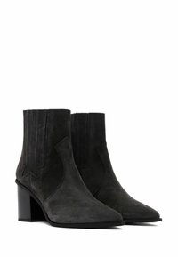 Black suede ankle boots with a pointed toe, block heel, and decorative side cutouts. Features vertical stitching at the shaft.