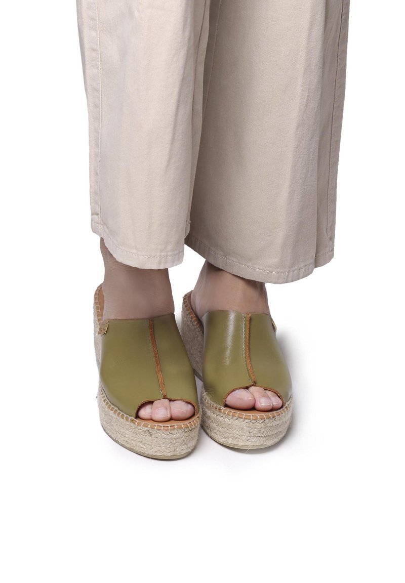 Gröna läderplattformssandaler med öppen tå, med en central dragkedja och jutevävda sulor. Kombineras med beige vida byxor.