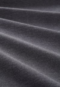 Tessuto grigio scuro con una trama liscia, caratterizzato da sottili linee diagonali create da pieghe, che mostrano una tessitura soffice e uniforme.