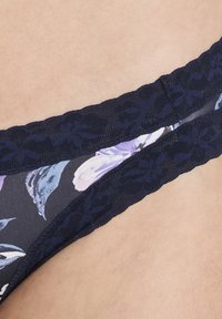 Marinblå blommig bikiniunderdel med spetsmidja och delikat blommönster. Tyget har en mjuk, slät textur med intrikata detaljer.