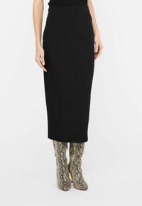 Schwarze Midi-Rock mit einem streamlined Design und glatter Textur, kombiniert mit kniehohen Stiefeln im Schlangenprint mit einem stabilen Absatz.