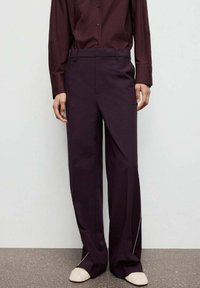 Bordeaux kleurige overhemd en wijde broek met een gladde textuur. Broek heeft witte zijkanten en een recht model.