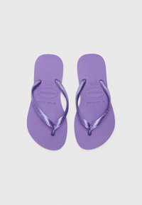 Violet flip-flopai, pagaminti iš gumos, su tekstūruotu padu, plonomis juostelėmis ir lygiu vidiniu paviršiumi, dekoruoti logotipu.