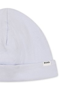 Chapeau en tricot côtelé bleu clair avec un revers replié. Présente une petite étiquette blanche avec du texte noir sur le côté. Texture douce, matériau élastique.