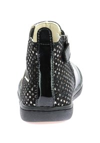 Stivali neri alla caviglia con intagli a forma di stella, dettagli in pelle verniciata lucida e chiusura con zip sul retro. Suola in gomma a profilo basso.