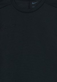 Svart Nike Dri-FIT treningstrøye med brodert Nike-svosh på venstre bryst og trykket svosh inni kragen.