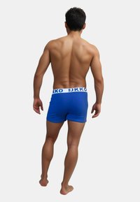 Blå boxerkalsonger med vit midjeresår som har varumärkesnamnet. Slät tyg, tät passform och längd till mitten av låret.