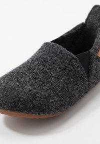 Grijze, gemakkelijke instap schoenen met elastische zijpanelen en een bruine rubberen zool. De textuur is zacht, met een vlezige oppervlakte en een afgeronde vorm.