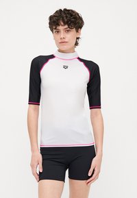 Vitt rash guard med kort ärm, svarta ärmar, rosa detaljer och logotyp. Tillverkad av stretchigt material; designad för användning som badkläder.
