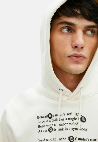 Weißer Hoodie aus weichem Stoff mit einer Kordelzugkapuze. Verfügt über schwarzen Text, der auf der Vorderseite in unterschiedlichen Größen und Stilen bedruckt ist, mit kreisförmigen Akzenten.