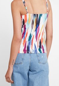 Kolorowy top na ramiączkach spaghetti z żywym, abstrakcyjnym wzorem w kolorach pomarańczowym, różowym, zielonym i niebieskim. Materiał ma gładkie wykończenie.
