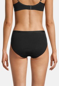 Schwarze Baumwollunterhose mit glatter Textur, ausgestattet mit einem gewellten Bund und minimalen Nähten, die einen engen Sitz bietet.