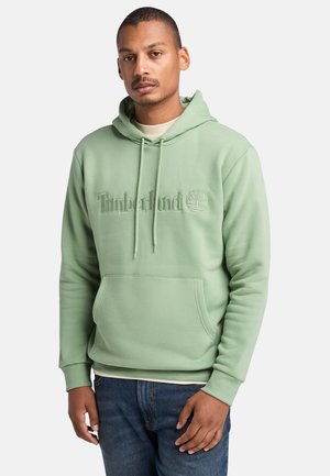 Lichtgroene hoodie van zacht materiaal, met een voorzak, trekkoorden en een reliëf 'Timberland' logo op de borst.