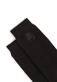 Calcetines negros hechos de un tejido de punto suave, con un patrón sutil más oscuro de logo en el tobillo. Diseño simple con puños acanalados.