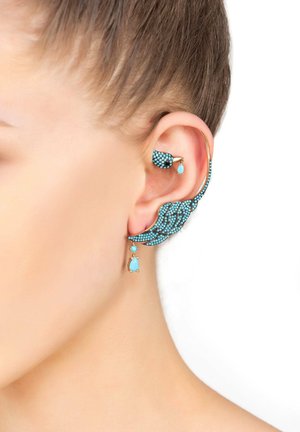 Blue gemstone ear jewelry features an intricate leaf design with gold accents and a dangling teardrop. Textured with small, shiny stones.