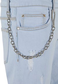 Jeans de mezclilla azul claro con una textura desgastada, que cuentan con múltiples bolsillos y una cadena plateada adjunta para accesorios o funcionalidad.