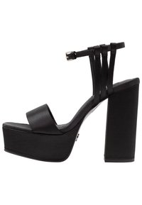 Černé platformové sandály s širokým předním páskem, páskem kolem kotníku a třemi svislými pásky. Hladký povrch, robustní podpatek a lesklé akcenty.