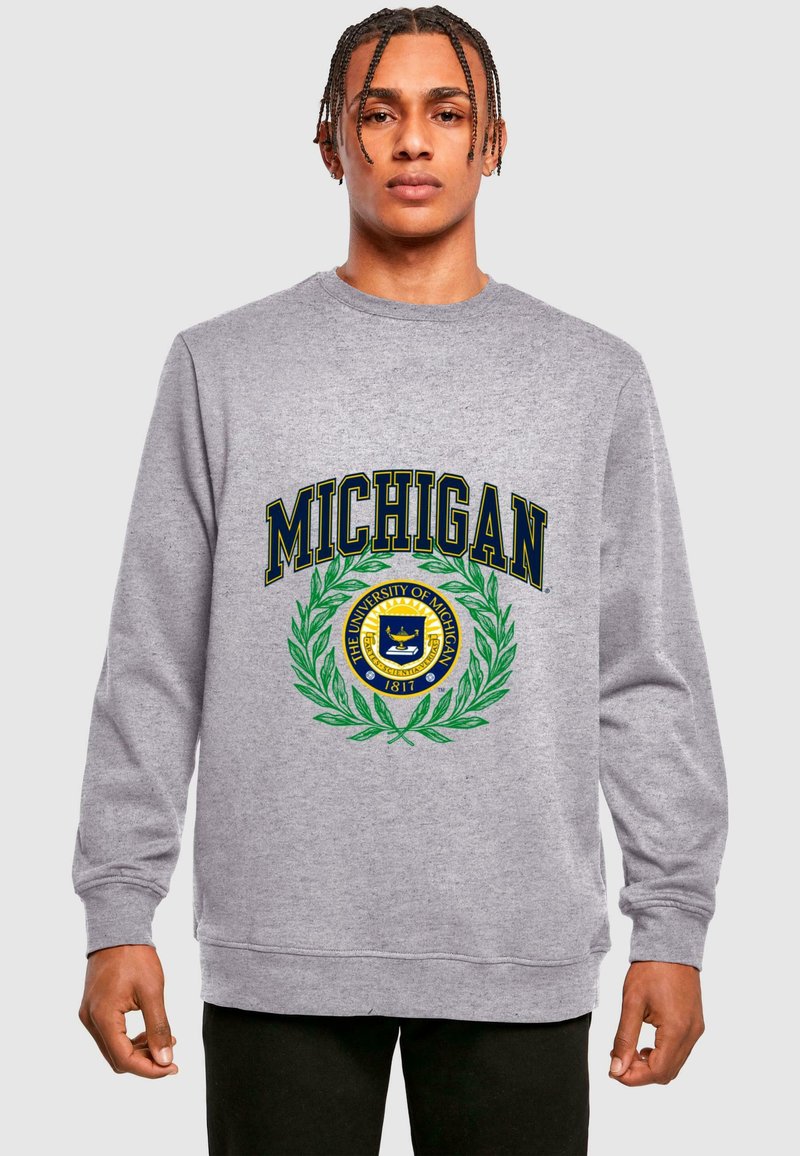 Szürke kapucnis pulóver hosszú ujjakkal, amelyen egy hangsúlyos Michigan címer található zöld babérsóval, tengerészkék felirattal és egy kerek kék emblémával.