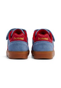 Niebiesko-czerwone zamszowe tenisówki z gumową podeszwą w kolorze naturalnym. Posiadają pasek na rzep oraz złote logo "hummel" na pięcie. Teksturowany wzór z tkaniny.
