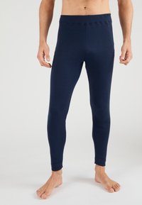 Navy blue leggings made of stretchy fabric, featuring a seamless waistband, tapered legs, and ankle cuffs. No visible patterns or hardware.