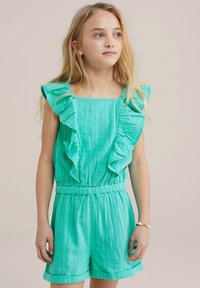 Tyrkysový overall s volánky vyrobený z texturované látky; čtvercový výstřih, elastický pas a ohrnuté manžety na šortkách.