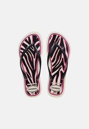 Par med Havaianas flip-flops med svarte og rosa zebrastriber, svarte stropper, og størrelsesetiketter synlige på beige såler.