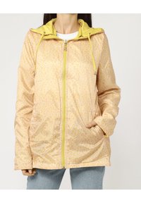 Chaqueta ligera con estampado amarillo, con cierre de cremallera, dos bolsillos y capucha. Tejido texturizado con un diseño sutil de puntos.